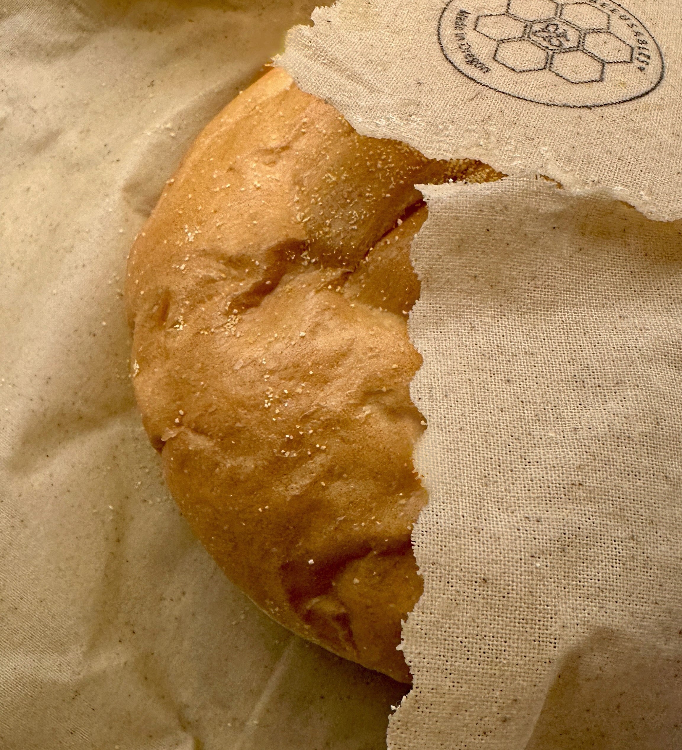 Partial view of a bread roll wrapped in a beeusable beeswax bread wrap.