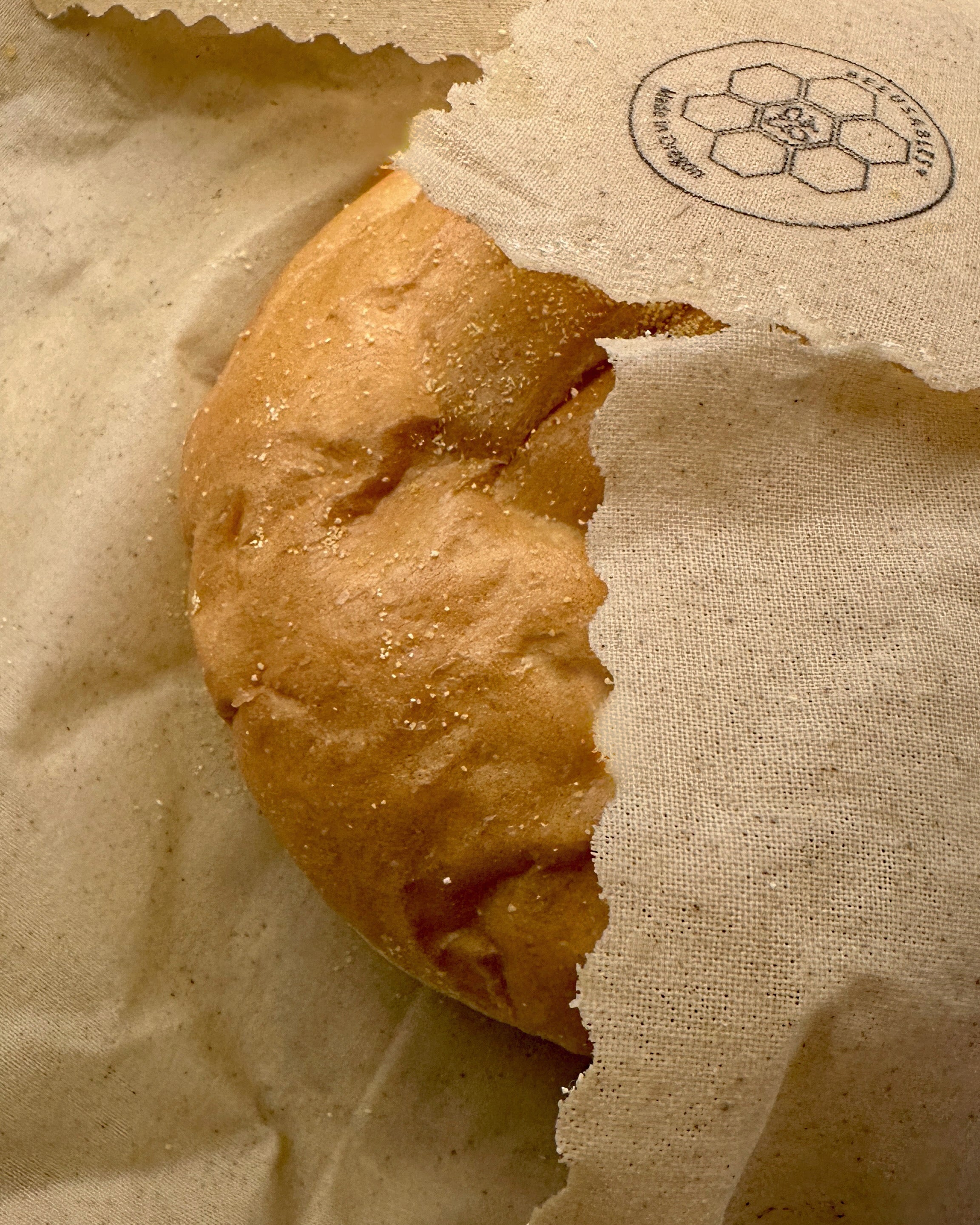 Partial view of a bread roll wrapped in a beeusable beeswax bread wrap.