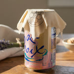 Can of La Croix with a Beeusable Beeswax Wrap covering the opening on a wooden surface