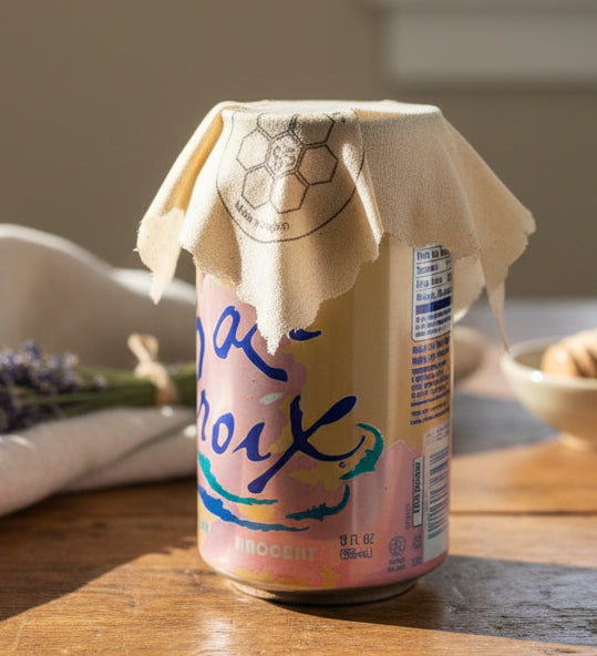 Can of La Croix with a Beeusable Beeswax Wrap covering the opening on a wooden surface