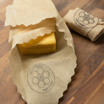 Block of cheese wrapped in a Queen Bee Beeusable Beeswax Wrap on a wooden surface