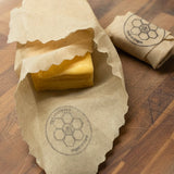 Block of cheese wrapped in a Queen Bee Beeusable Beeswax Wrap on a wooden surface