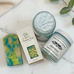 Three beauty products including a jar of cream, a bar of soap, and a container labeled 'Heavenly' on a white background.