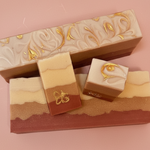 Three layered soap bars with decorative designs on a pink background