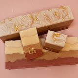 Three layered soap bars with decorative designs on a pink background