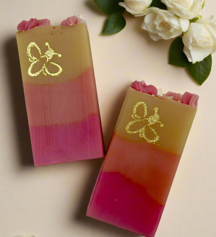 Two layered soap bars with a Bee Logo design on a beige background with white flowers.