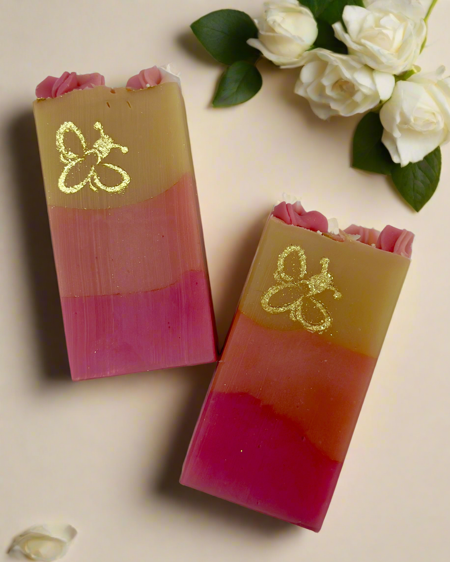 Two layered soap bars with a Bee Logo design on a beige background with white flowers.