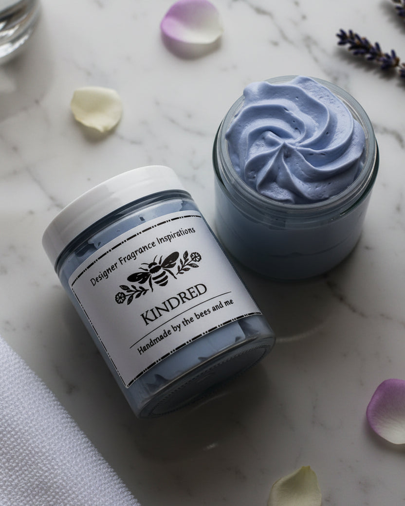 Jar of blue whipped body butter on it's side next to an open jar showing the contents.