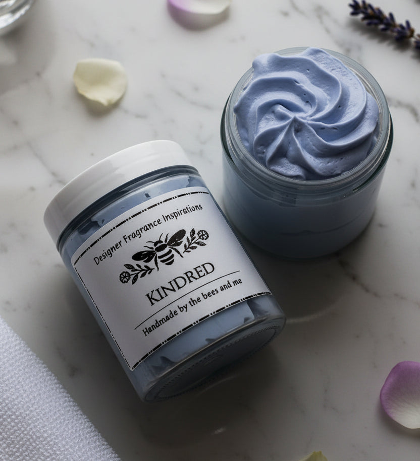 Jar of blue whipped body butter on it's side next to an open jar showing the contents.