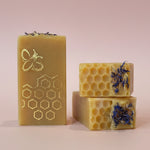 Three bars of soap with honeycomb and floral designs on a kitchen counter.