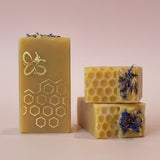 Three bars of soap with honeycomb and floral designs on a kitchen counter.