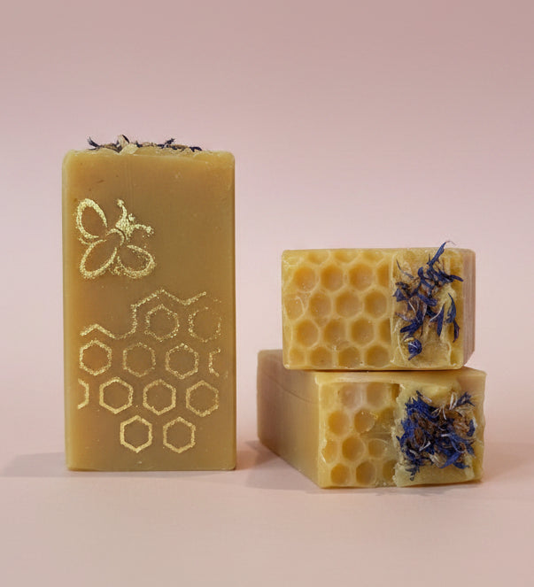 Three bars of soap with honeycomb and floral designs on a kitchen counter.