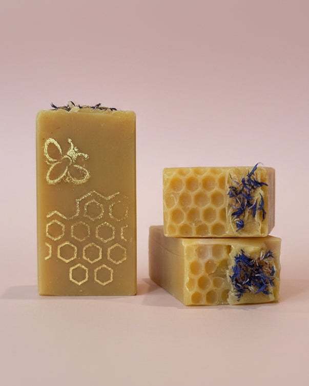 Three bars of soap with honeycomb and floral designs on a kitchen counter.