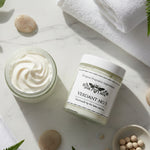 Two jars of light golden whipped body butter, one open, showing the contents 