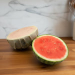 Half cut watermelon on a counter with a beeusable beeswax wrap covering one.