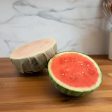 Half cut watermelon on a counter with a beeusable beeswax wrap covering one.